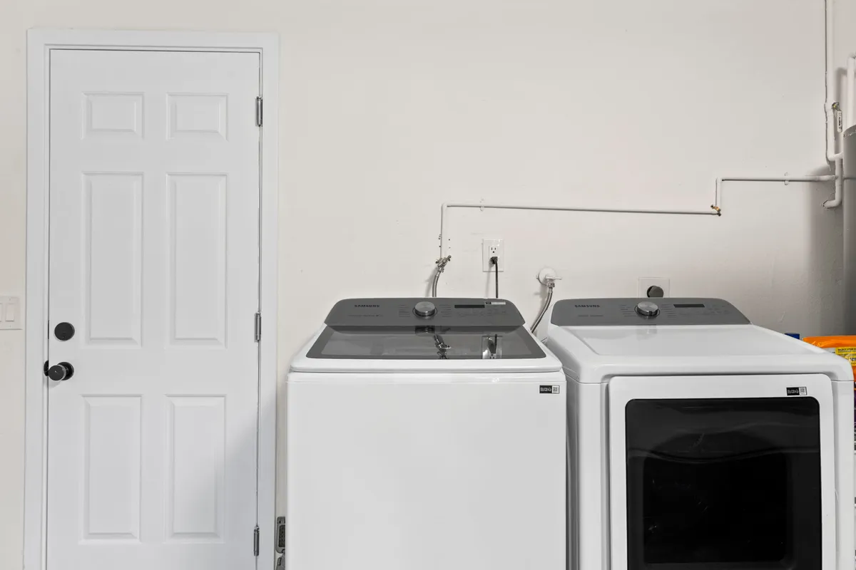 A functional laundry area with a washing machine, dryer, and white door, all arranged efficiently for easy use. The clean, tidy setup suggests a practical solution for longer or more comfortable stays.