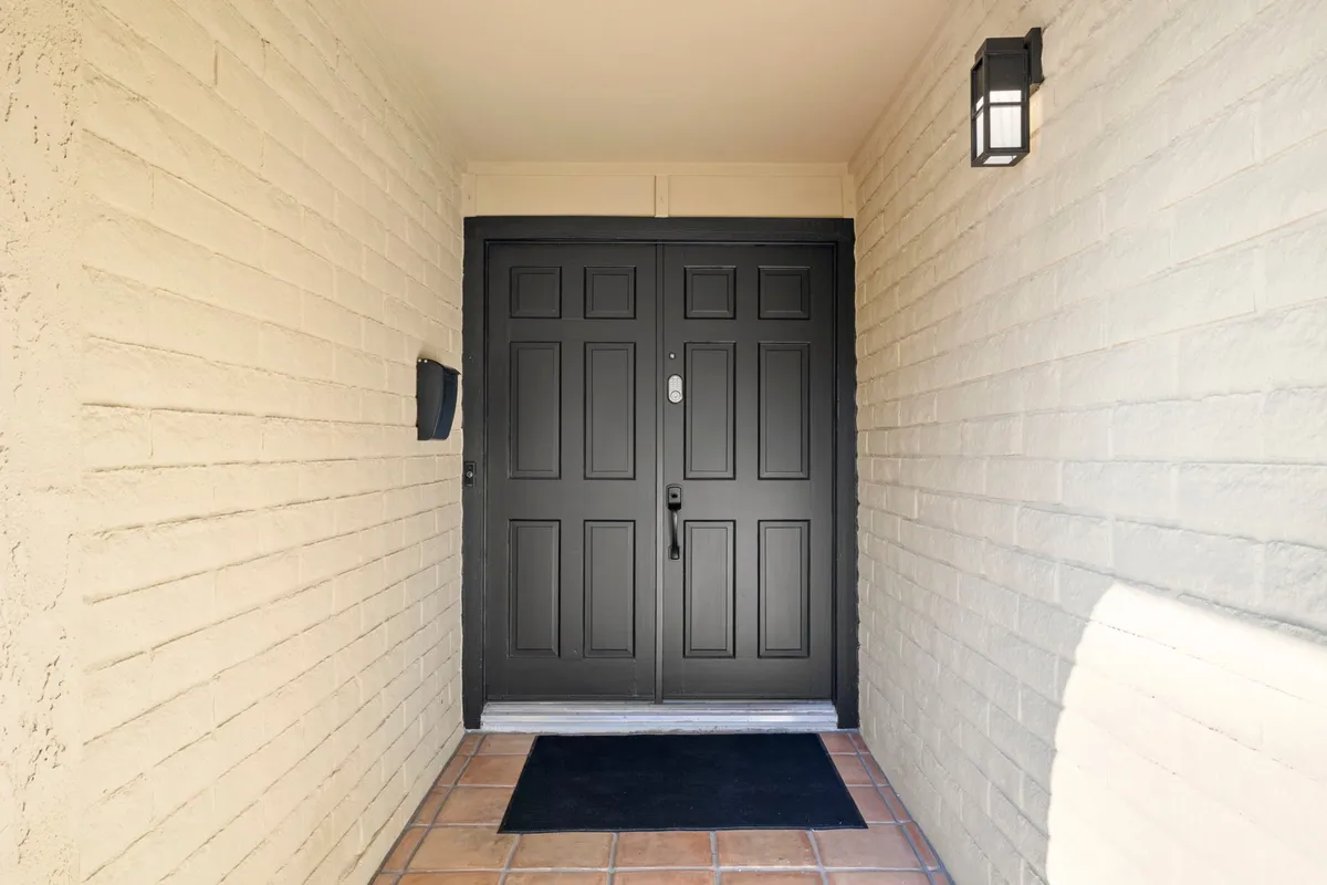 A view of a double front door with a welcome mat and a stylish light fixture overhead. The entryway is clean, modern, and inviting, setting the tone for the experience as soon as you step inside.
